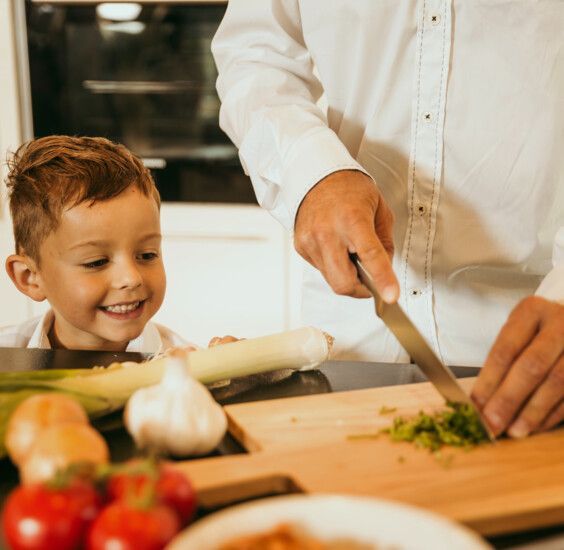 Kinder sieht dem Vater beim Kochen zu.