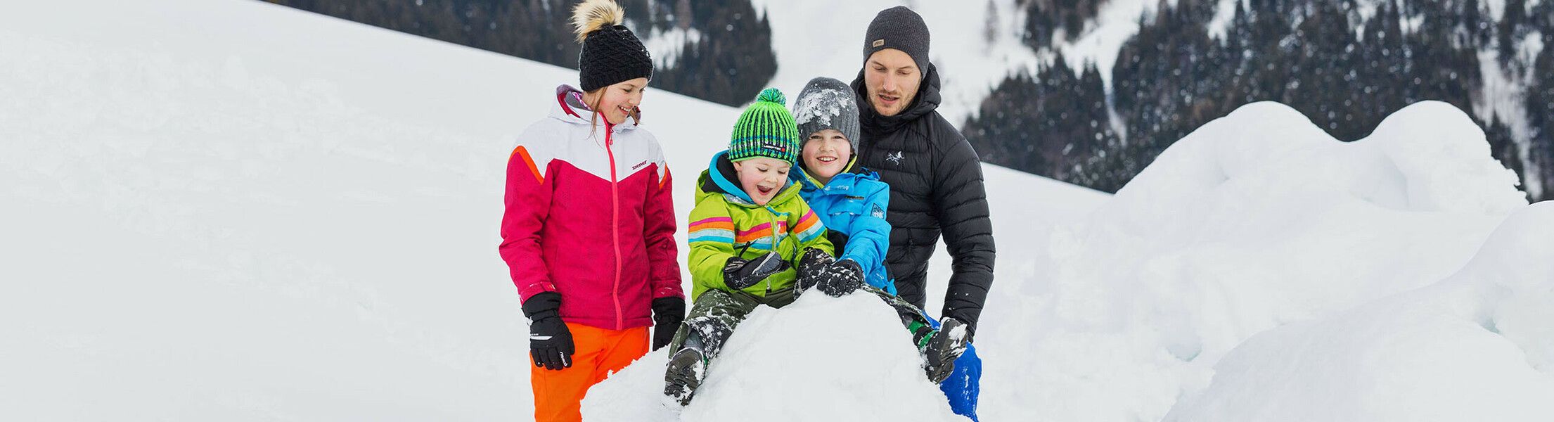 Familie baut Schneemann im Winter im Salzburger Land